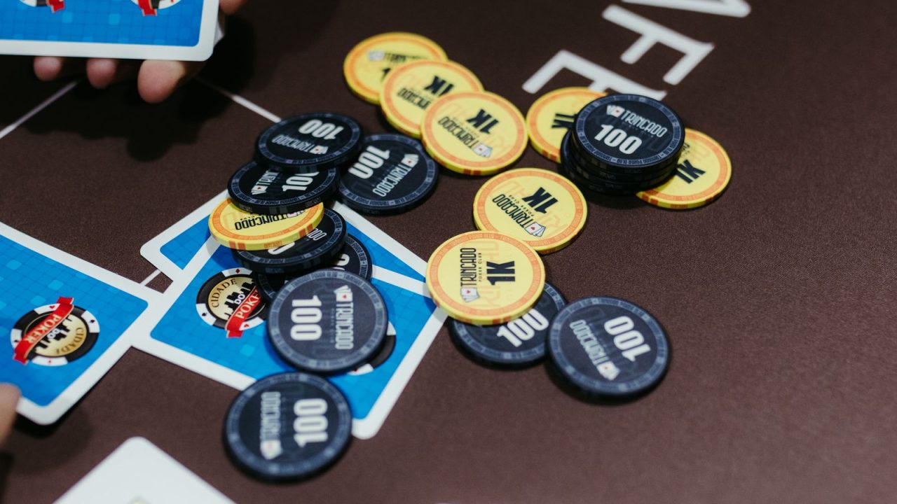 A close-up of poker chips and cards on a table during a game of Texas Hold'em.